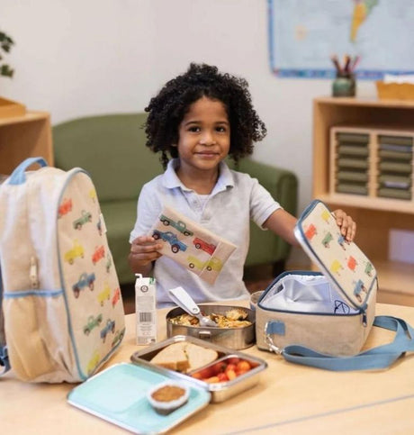 Young child at school with eco-friendly lunch containers, matching car-patterned backpack, and lunch bag from Kolkid.