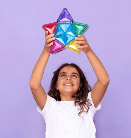 Smiling child holding a colorful magnetic star toy above their head against a purple background, symbolizing creativity and play from Kolkid.