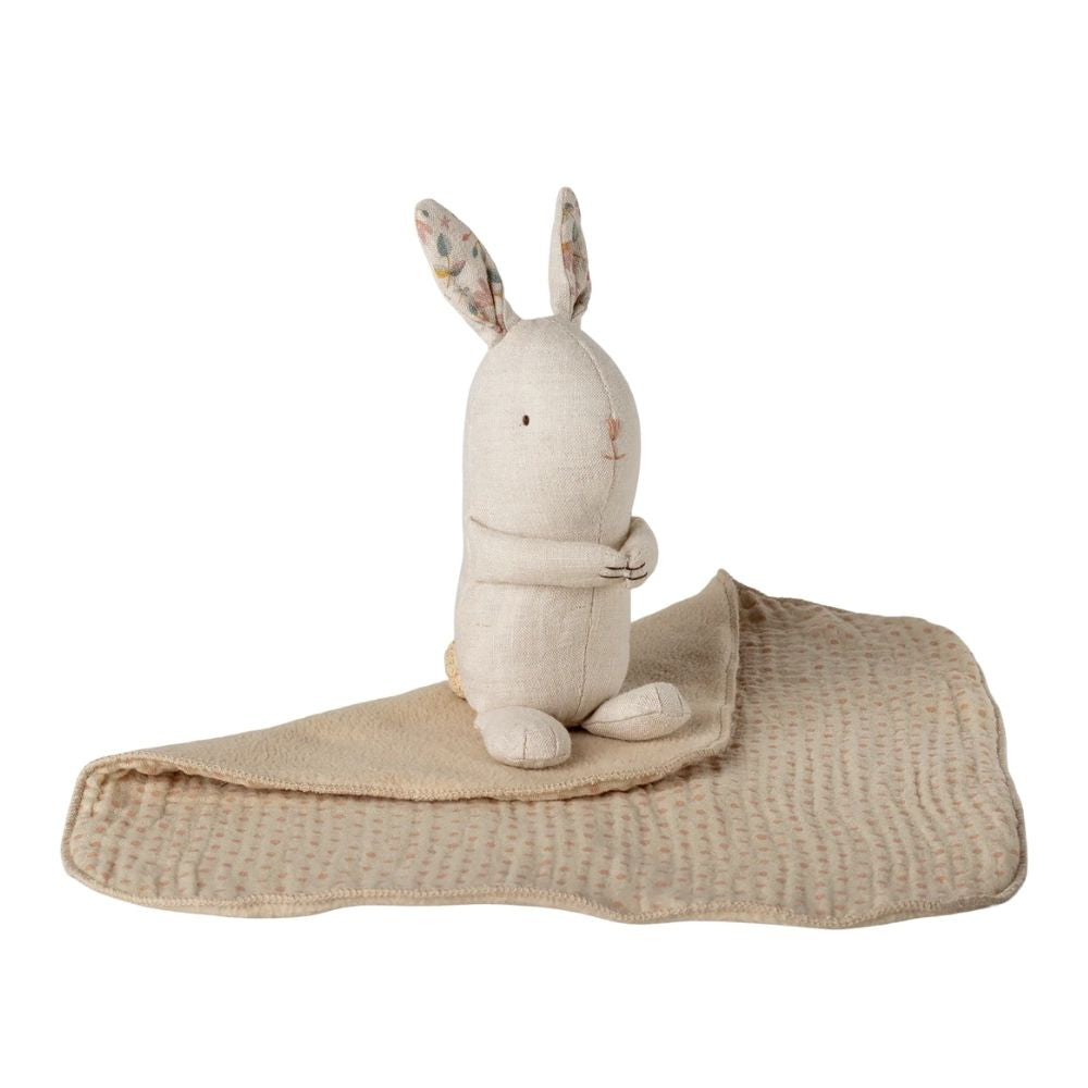 Stuffed rabbit toy with a beige blanket on a white background
