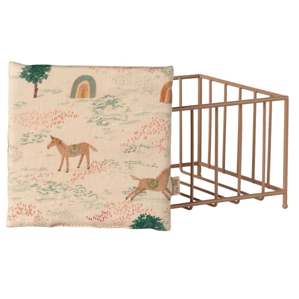 Baby crib with a decorative blanket featuring horse illustrations on a white background