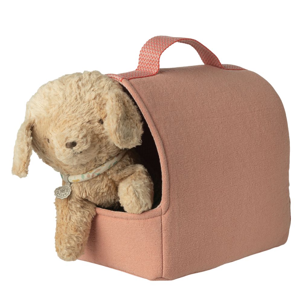 Pink pet carrier with a beige dog inside on a white background