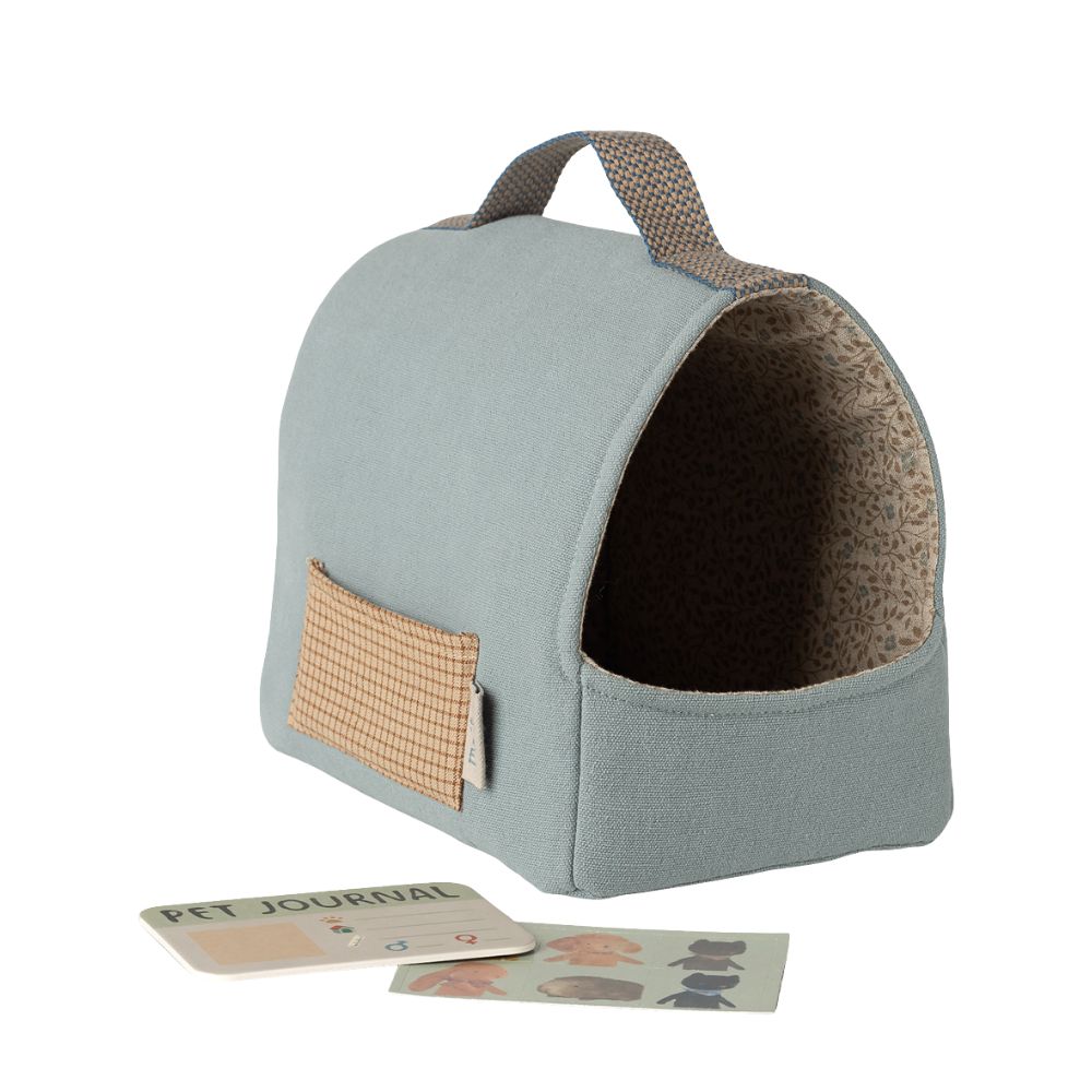 Pet bed with a handle and a small pouch, accompanied by a pet journal on a white background.