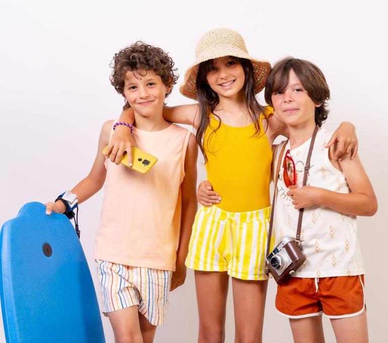 Three young children posing for a vacation photo in beachwear