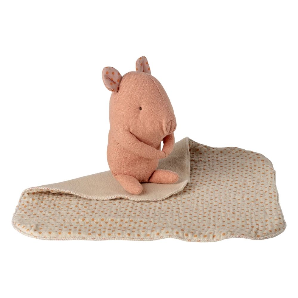 Pink plush hippo toy on a beige blanket with white background