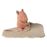 Pink plush hippo toy on a beige blanket with white background