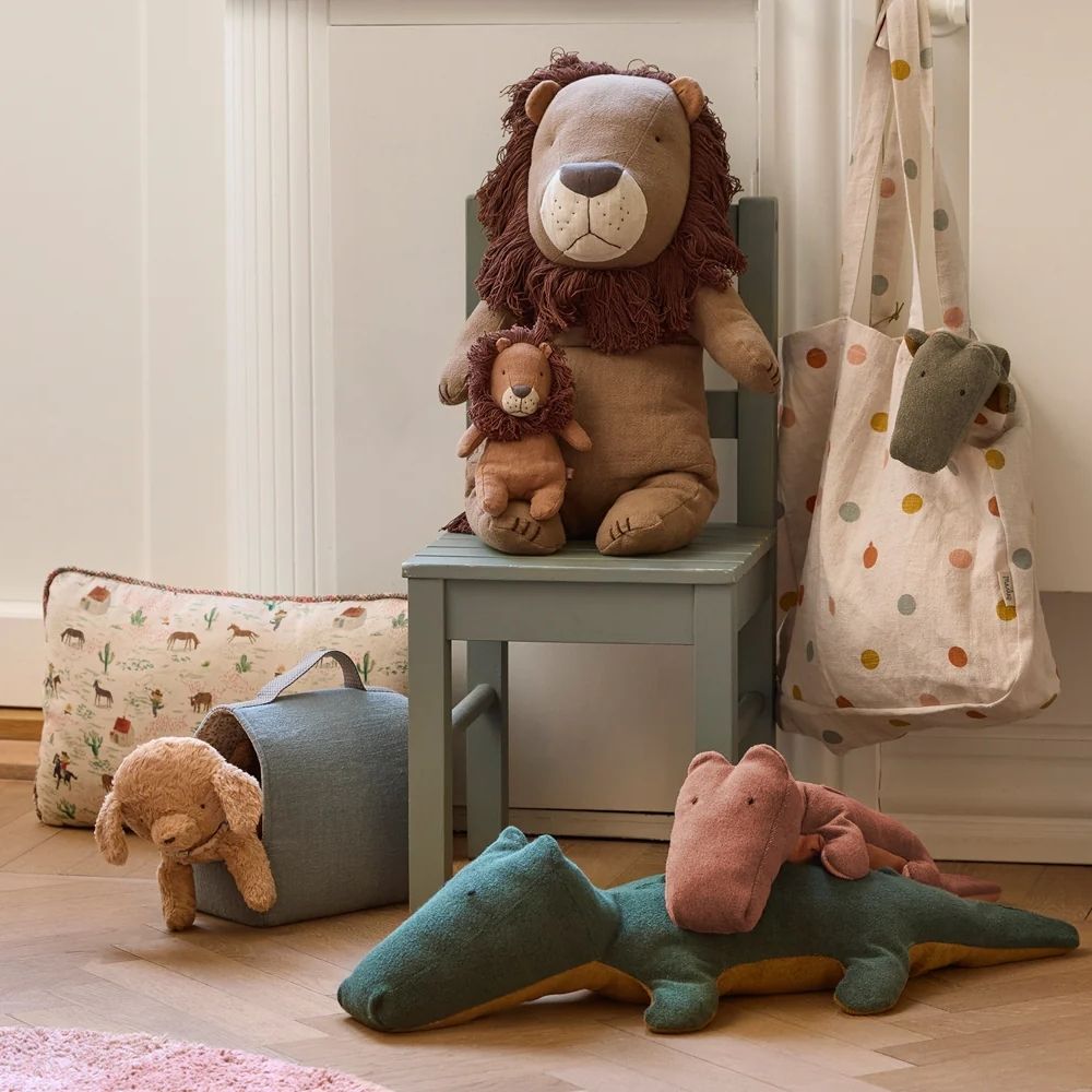 Children's room with plush toys including a lion, elephant, and bear on a chair and floor.