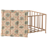 Floral-patterned crib bumper next to a baby crib on a white background