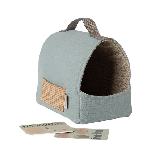 Pet bed with a handle and a small pouch, accompanied by a pet journal on a white background.