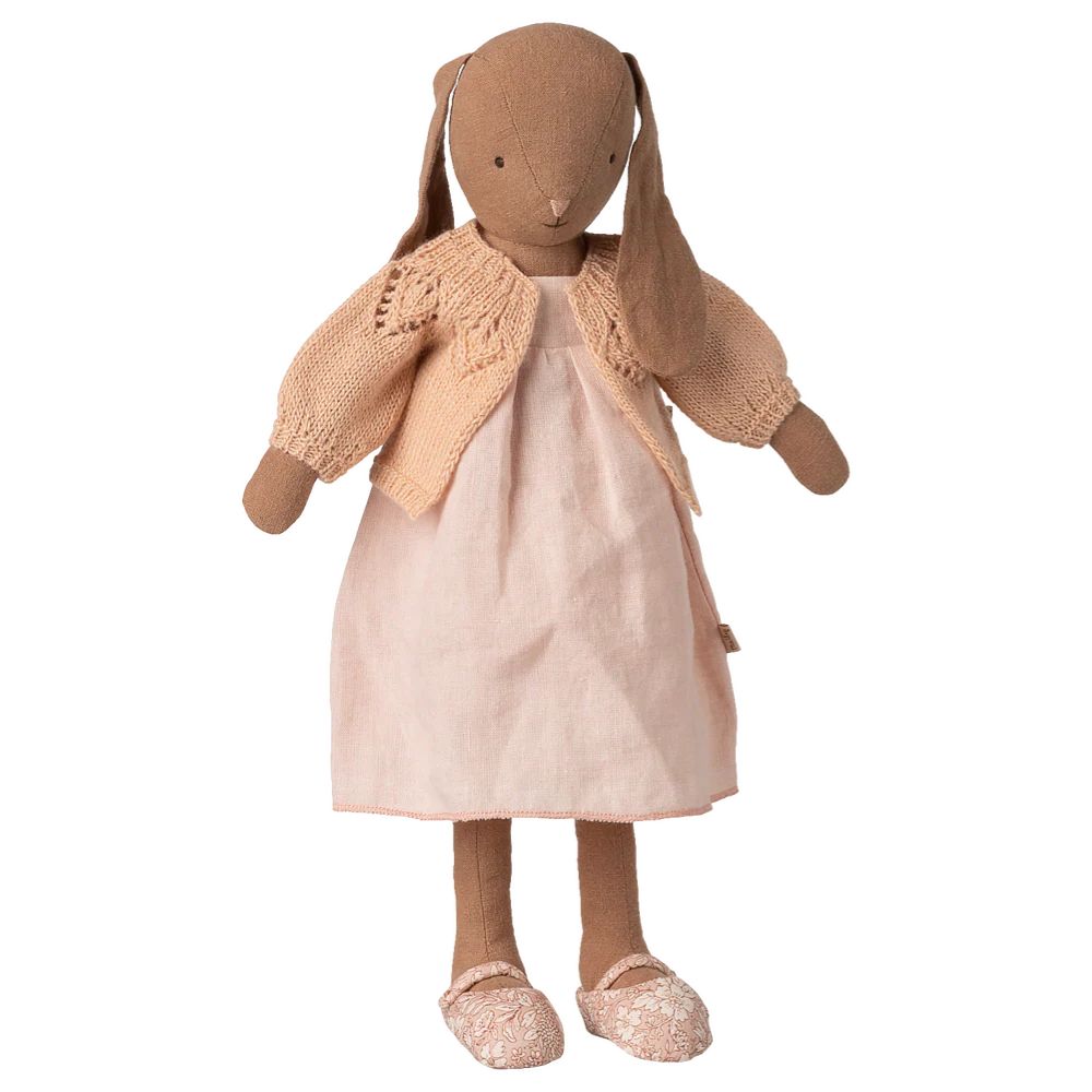 Stuffed rabbit doll wearing a beige knitted cardigan and pink dress on a white background