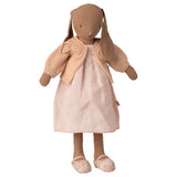 Stuffed rabbit doll wearing a beige knitted cardigan and pink dress on a white background